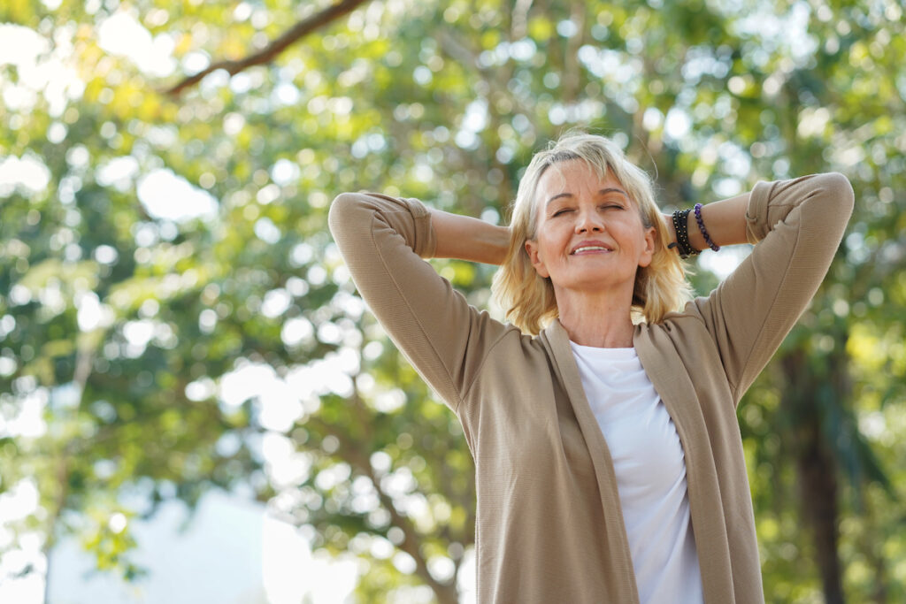 Senior Woman with Eyes Closed Breathing in Fresh Air Outside_Dimensions of Wellness